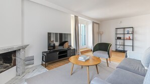Ein modernes Wohnzimmer mit Kamin, Flachbildfernseher, Sofa, Couchtisch und Bücherregal.