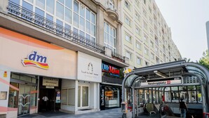 En byggnad med ett stort fönster, en busshållplats och en butik med en väl synlig skylt.