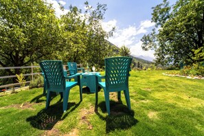 A grassy outdoor area with a table and chairs, surrounded by trees and a fence. - Hotel Gulsar pahalgam  (Pahalgam)