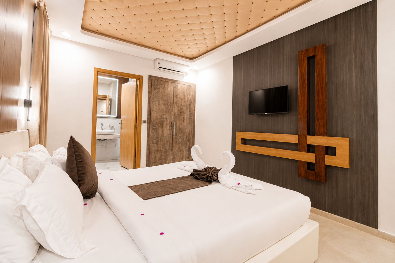 Une chambre d’hôtel moderne équipée d’un lit, d’une télévision et d’un mur décoratif en bois.