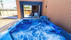 Un jacuzzi con vistas a un patio, una puerta corrediza de vidrio y una silla de mimbre.