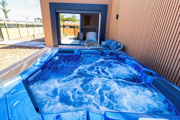 A hot tub with a view of a patio area, a sliding glass door, and a wicker chair. - rose garden resort marrakech (Marrakech)