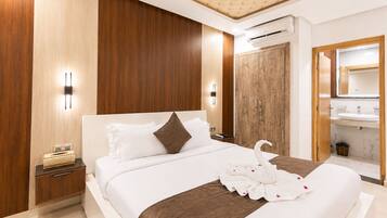 A modern hotel room with a large bed, wooden panel walls, a built-in wardrobe, a vanity with a mirror, and an air conditioning unit.