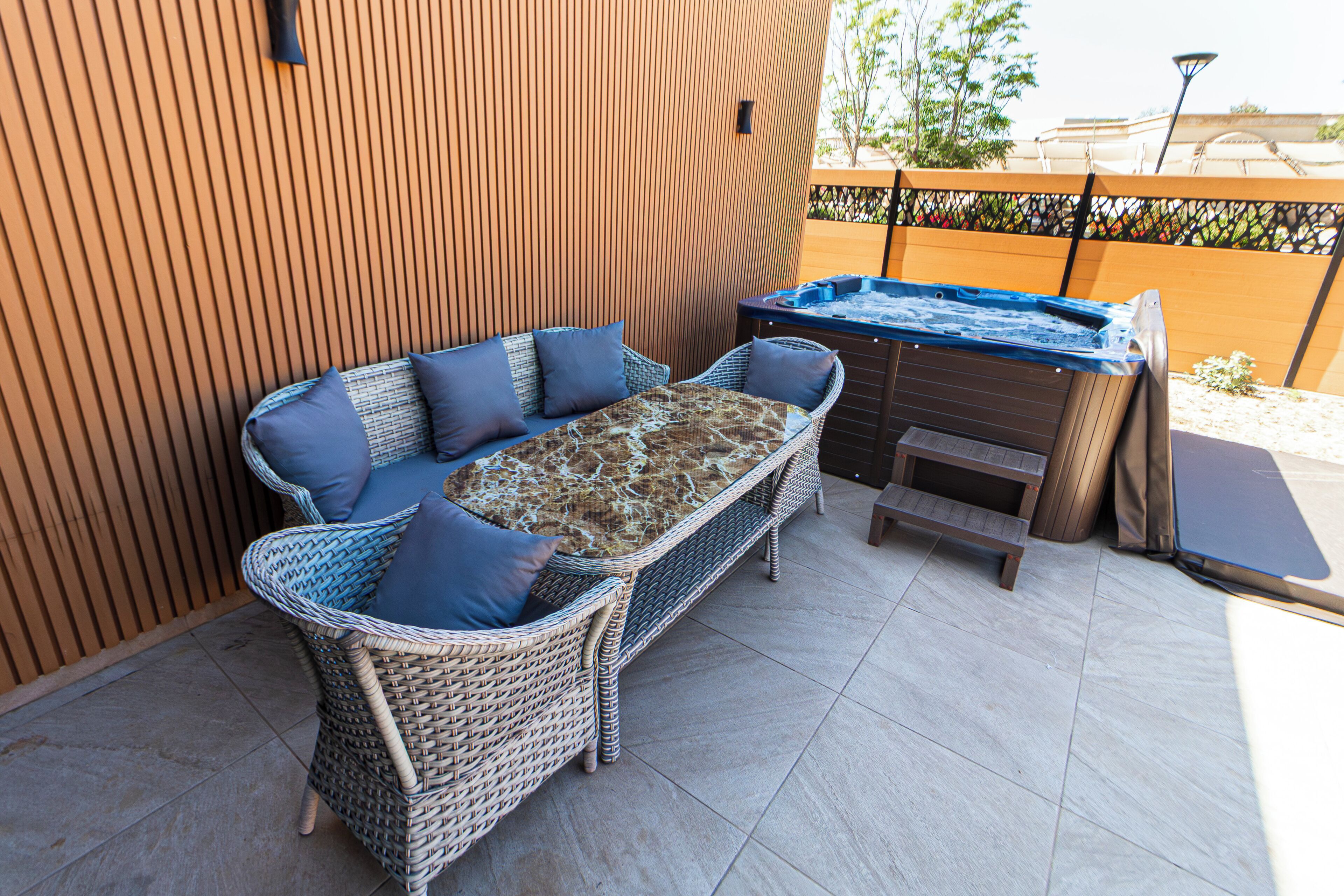 Un canapé en osier avec des coussins, un jacuzzi et un mur en bois.
