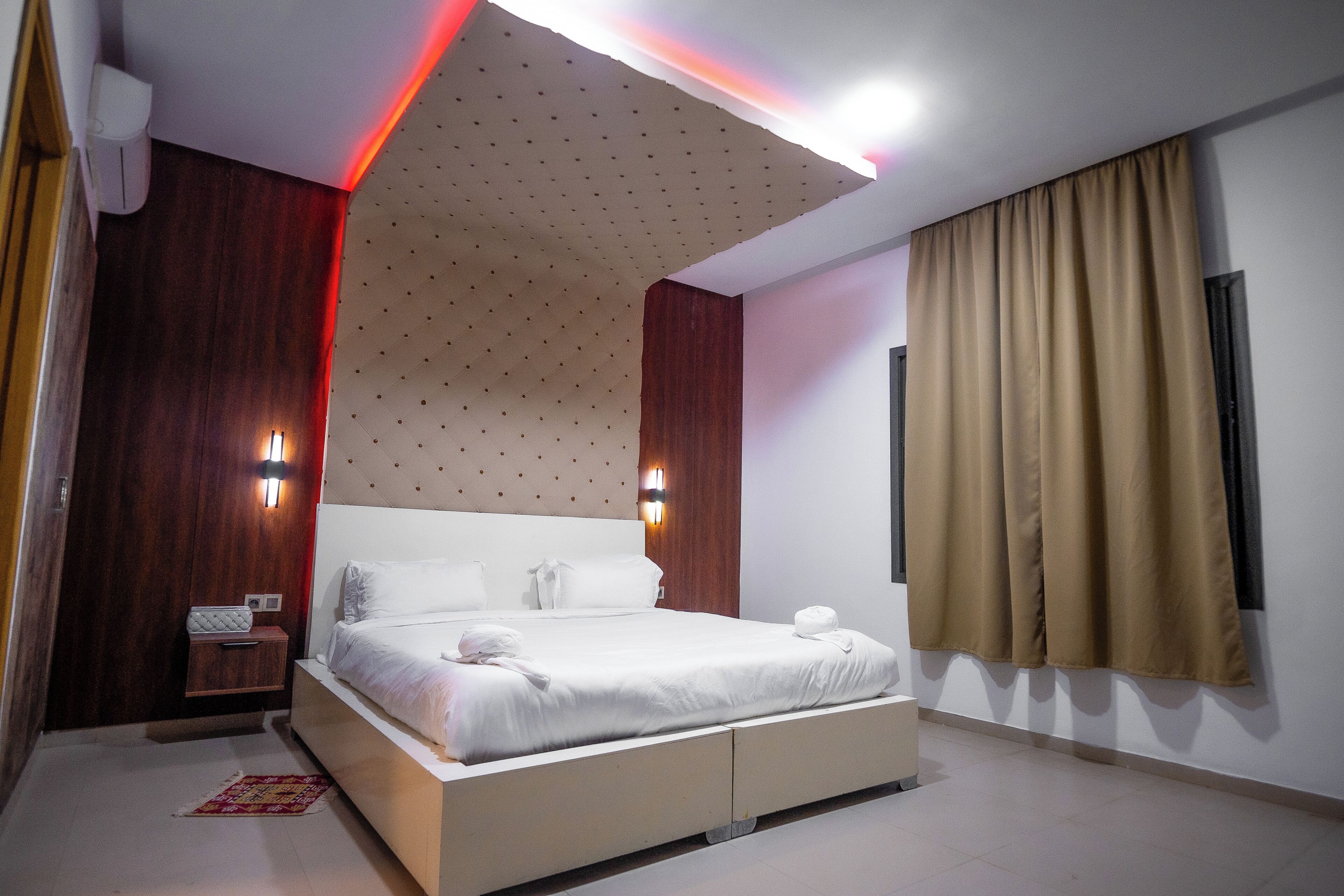 Una habitación de hotel moderna con una cama grande, un muro decorativo de madera y un techo con un diseño original.