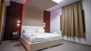 Una habitación de hotel moderna con una cama grande, un muro decorativo de madera y un techo con un diseño original.