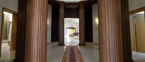 A spacious lobby with high ceilings, large wooden columns, and a central carpeted walkway leading to a seating area.