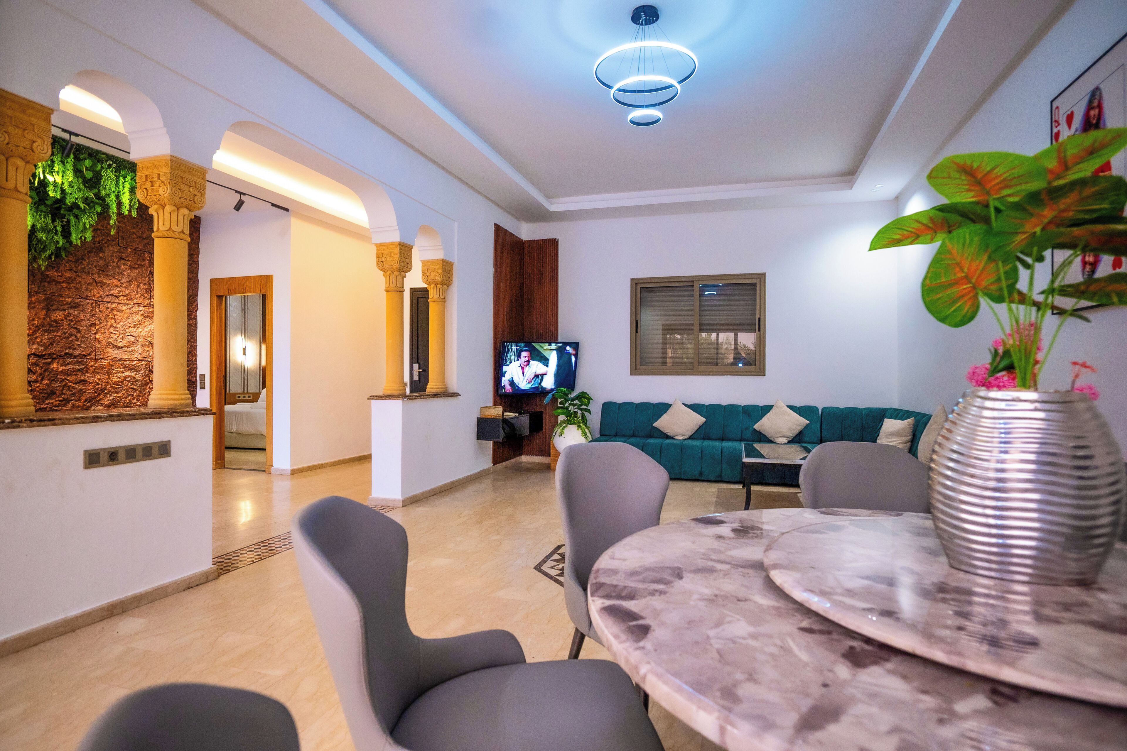 Una sala de estar moderna con una mesa de mármol, sofás grises y un televisor.