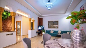 Una sala de estar moderna con una mesa de mármol, sofás grises y un televisor.