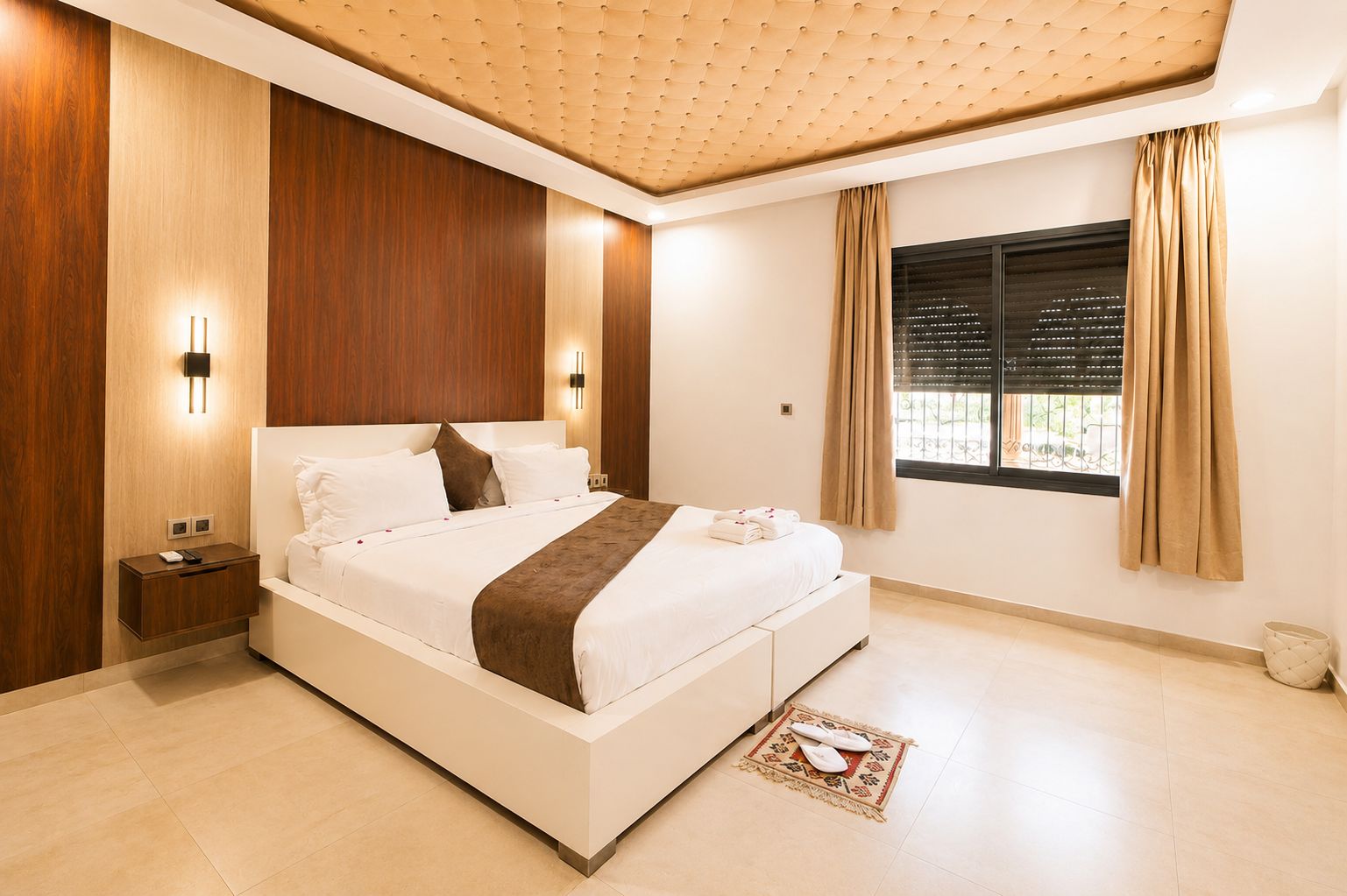 Un dormitorio moderno con una cama grande, mesitas de noche, una ventana con cortinas y un techo con un diseño original.