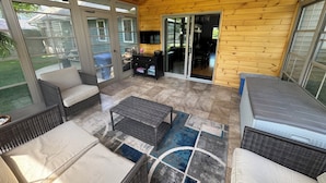 Ein überdachter Patio-Bereich mit Korbmöbeln, einem Deckenventilator und Blick auf den Garten.