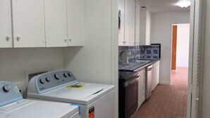 Un espace buanderie équipé d’un lave-linge et d’un sèche-linge, avec un pare-feu en carrelage et un sol en briques.