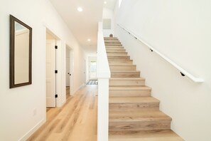 Una escalera de madera con paredes blancas que conduce a un piso superior.