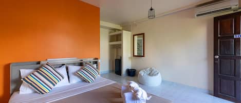Quarto de hotel com cama, guarda-roupa, aparelho de ar condicionado e porta com número.