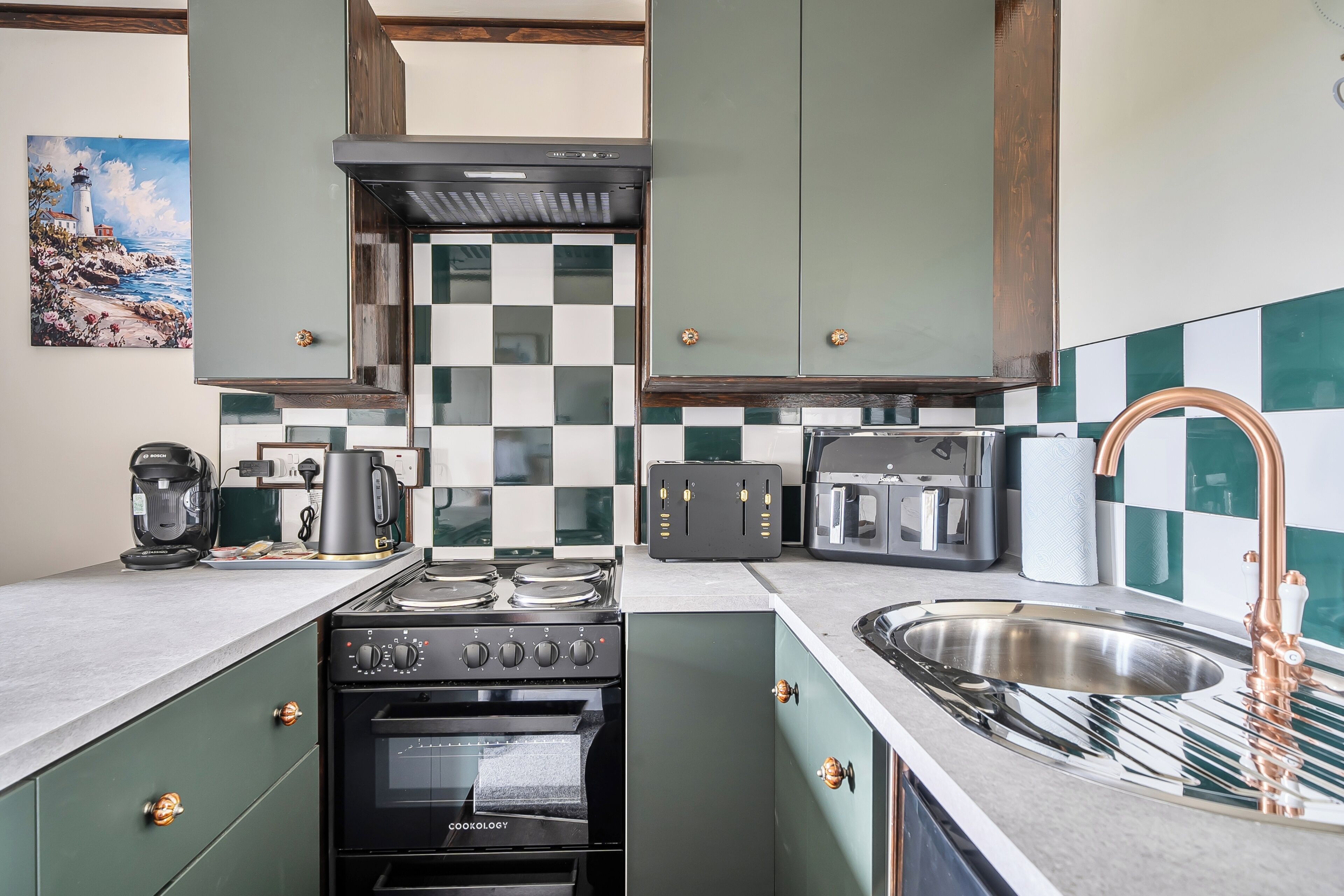 A kitchen with a stove, oven, and a sink with a copper faucet.