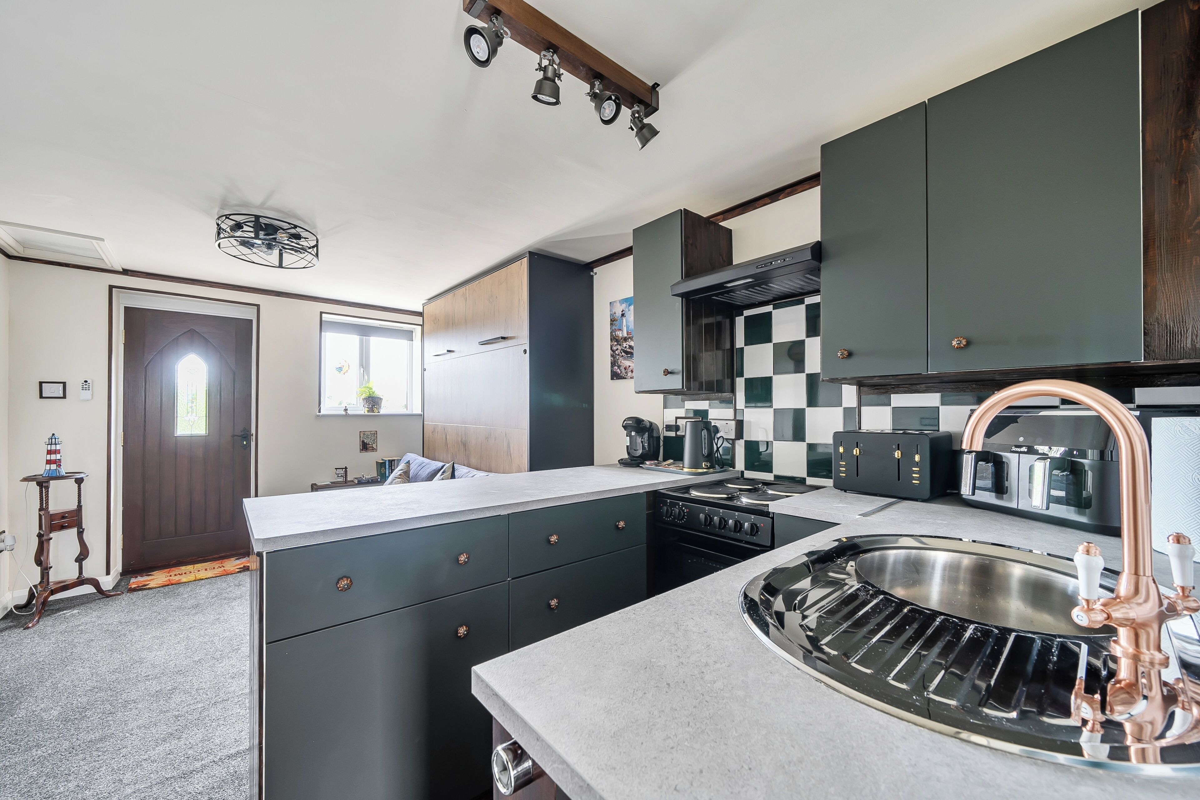 Una cocina moderna con una isla central, electrodomésticos integrados y un amplio lavamanos de acero inoxidable.