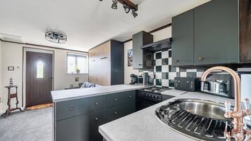 Una cocina moderna con una isla central, electrodomésticos integrados y un amplio lavamanos de acero inoxidable.