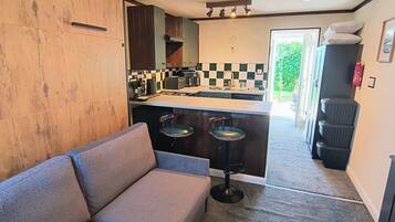A compact kitchen with a bar area, a sofa, and a view of the outdoors.