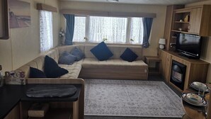 Et opholdsområde med sofa, fjernsyn, et lille bord og et tæppe.