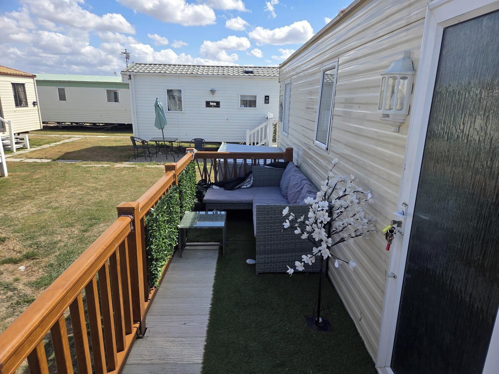 Een stacaravan met terras, zitplaatsen buiten en een kleine tuin.