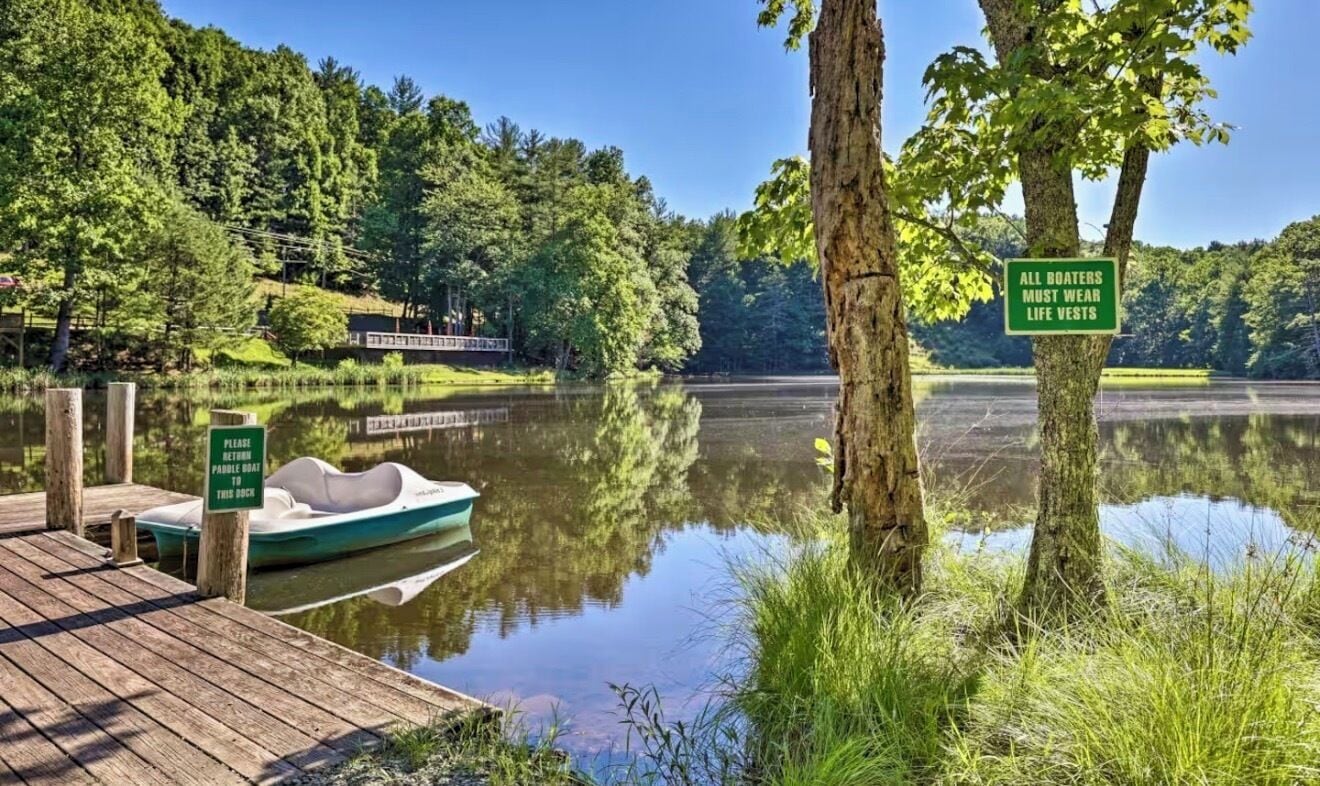 A calm lake with a dock, a boat, and signs indicating safety rules for boaters.