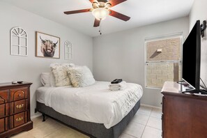 A bedroom with a bed, a ceiling fan, a dresser, a TV, and a window with a brick pattern. - Foothills Golf Escape - Phoenix Pool House backing up to Foothills Golf Club (Phoenix)