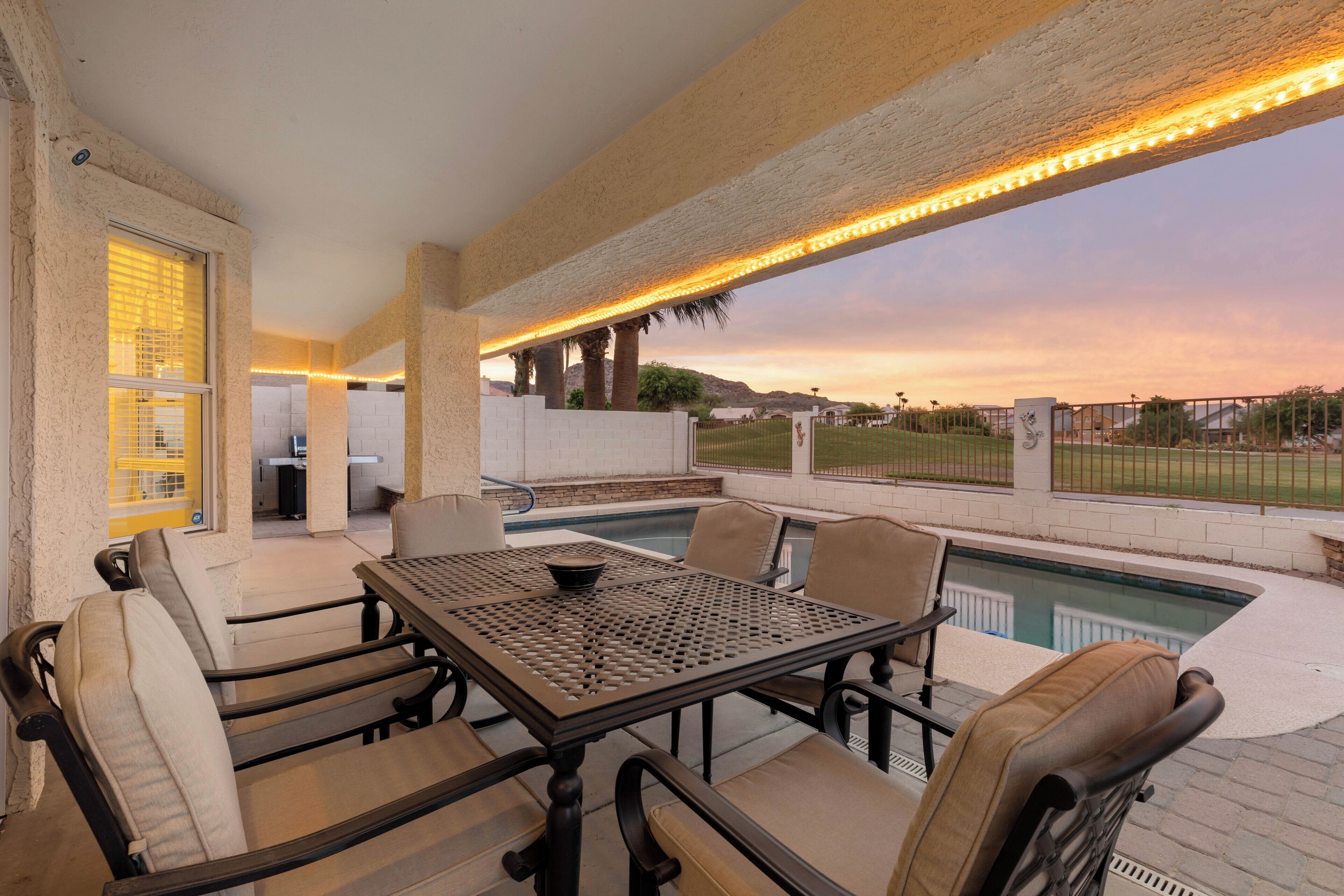 An outdoor patio with a pool, seating, and a view of the landscape.