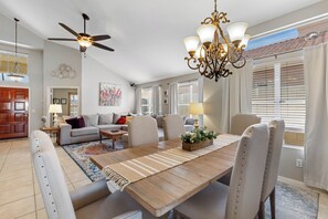 A spacious living room with a dining table, chairs, a ceiling fan, and a chandelier. - Foothills Golf Escape - Phoenix Pool House backing up to Foothills Golf Club (Phoenix)