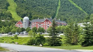 A large, multi-story building with a red facade and a white dome, surrounded by lush greenery and a mountain backdrop. - Summer, wedding and foliage destination in Warren (Warren)