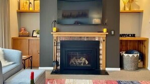 A living room with a fireplace, a flat-screen TV mounted above it, a sofa, and a coffee table. - Summer, wedding and foliage destination in Warren (Warren)