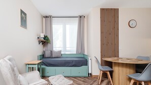 A room with a bed, a desk, a chair, and a small table with a clock on the wall. - Nawrot Downtown Chic Studio #A (Łódź)