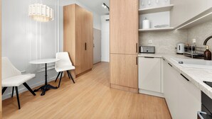 A modern kitchen with white cabinetry, a dining area with a round table and chairs, and a pendant light. - Kalwaryjska Signature Bright Studio (Kraków)