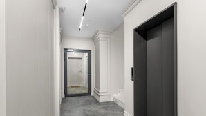 A hallway with a modern elevator, a door leading to another room, and a tiled floor. - Kalwaryjska Signature Bright Studio (Kraków)