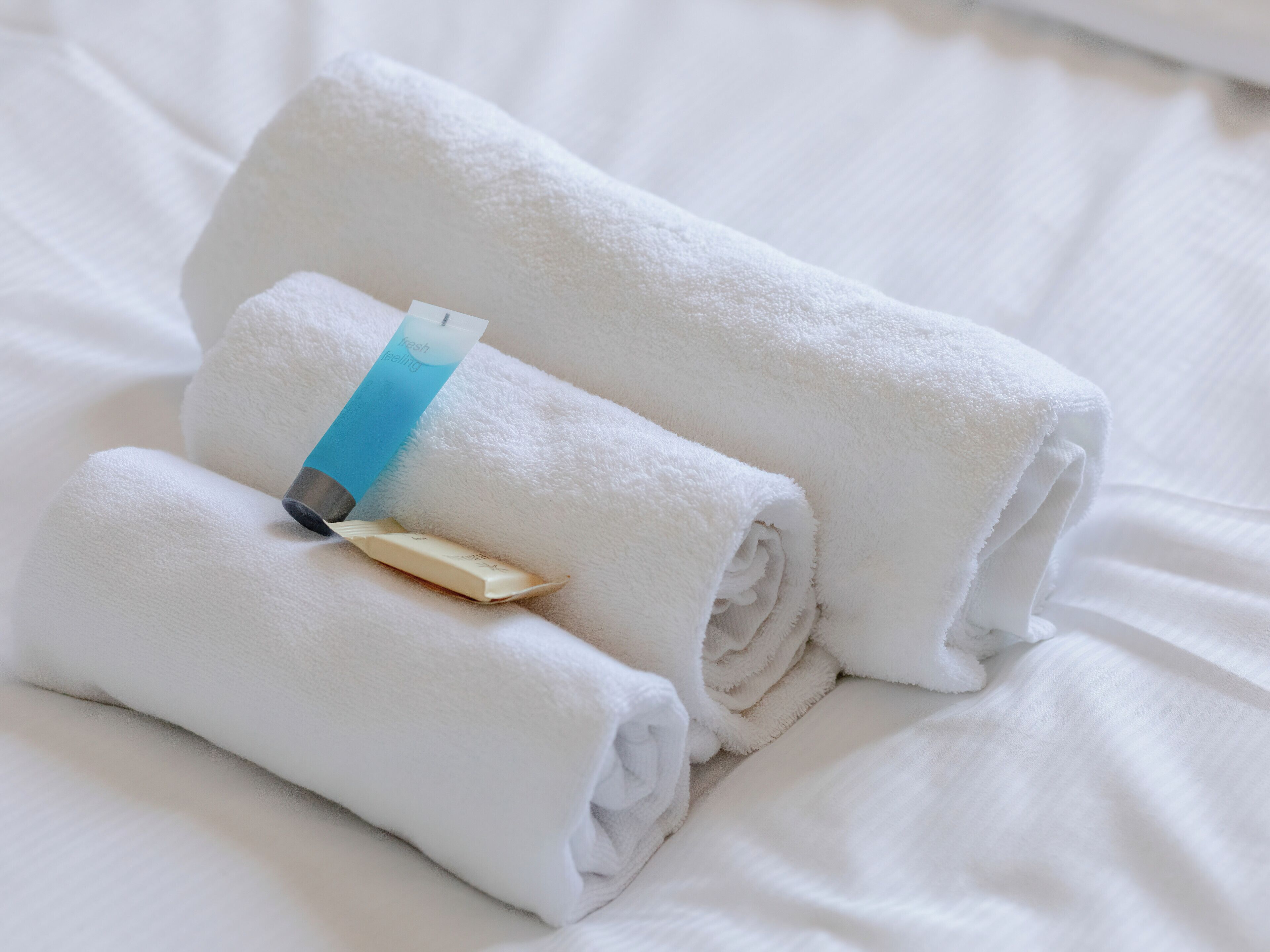 Neatly folded white towels on a bed.