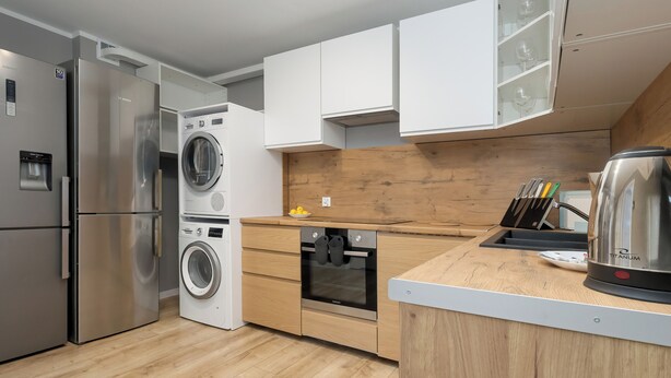 A modern kitchen with stainless steel appliances, wooden cabinets, and a built-in oven. - Jagiellońska Central Guest Spot #2 (Szczecin)