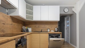 Una cucina moderna con mobili in legno, lavastoviglie integrata e un orologio appeso al muro.