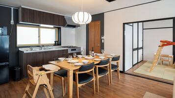 A modern kitchen with a dining area, wooden flooring, and a large window.