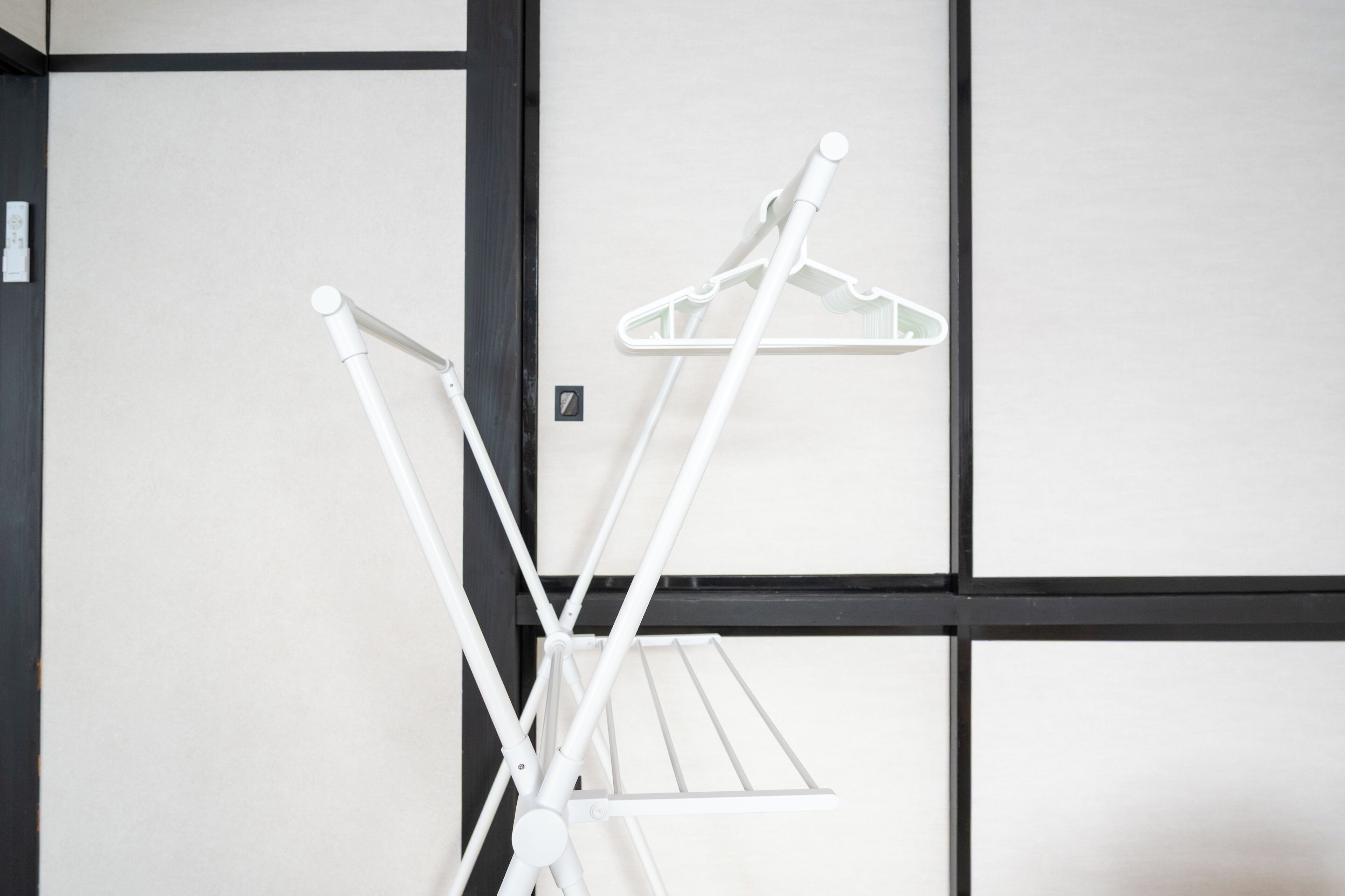 A white drying rack with a hanger and a drying cloth against a wall with black and white paneling.