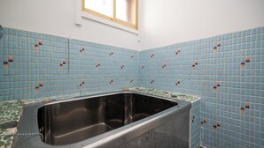 Ein Badezimmer mit Badewanne, Fenster und blauen Fliesen.