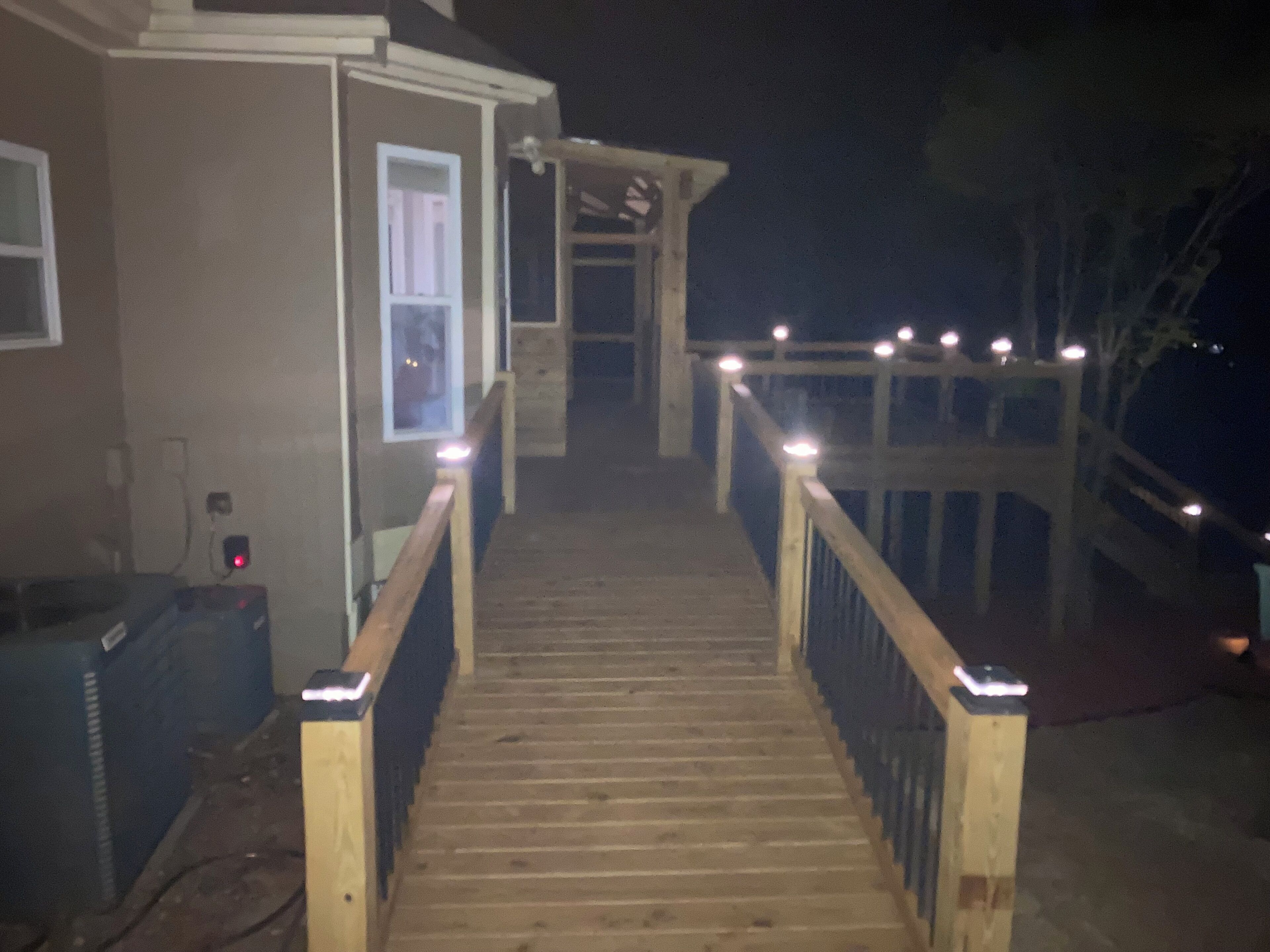 A wooden staircase leading to a deck with railings and lights.