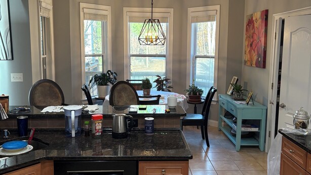 A kitchen with a central island, a dining area with a table and chairs, and a view of the outdoors through windows. - Main level access = 2 BR, 2 private baths, and much more. Wheelchair accessible. (Braselton)