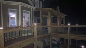 A multi-level wooden deck with railings, a covered area, and a view of a house with windows. - Main level access = 2 BR, 2 private baths, and much more. Wheelchair accessible. (Braselton)