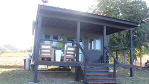 A two-story building with a covered porch, wooden steps, and a small outdoor seating area.