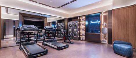Un gimnasio moderno con cintas de correr, elípticas y una zona de lavandería.