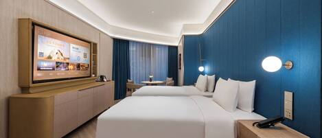 A hotel room with a large bed, a desk, a chair, a TV mounted on the wall, and a blue accent wall.