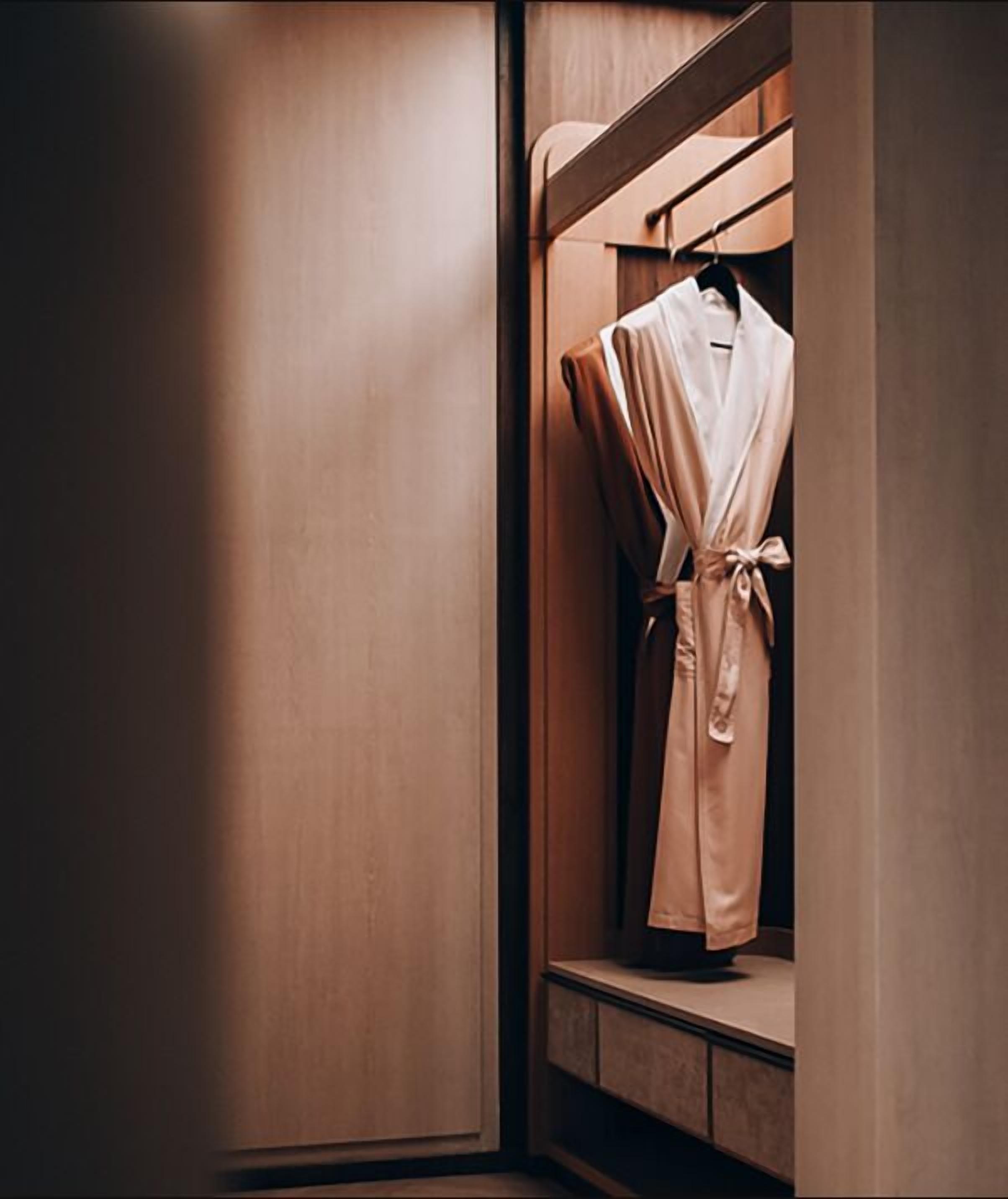A wooden wardrobe with a robe hanging inside.