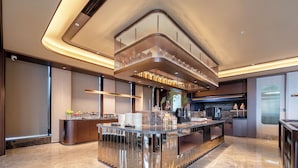A modern bar area with a curved counter, overhead lighting, and a mezzanine level with bottles. - Crystal Hotel Hangzhou Binjiang Powerlong (Hangzhou)