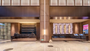 A modern lobby with a central column, a reception desk, and a digital information kiosk. - Crystal Hotel Hangzhou Binjiang Powerlong (Hangzhou)