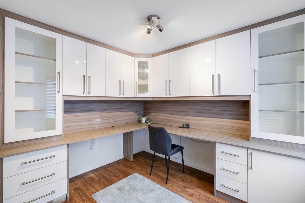 Una cucina moderna con mobili bianchi, un piano di lavoro in legno e una sedia nera.