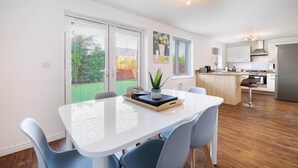 A modern kitchen with a central island, white cabinetry, and a stainless steel refrigerator. - Entire 5 Bed home in Bristol United Kingdom (Pucklechurch)